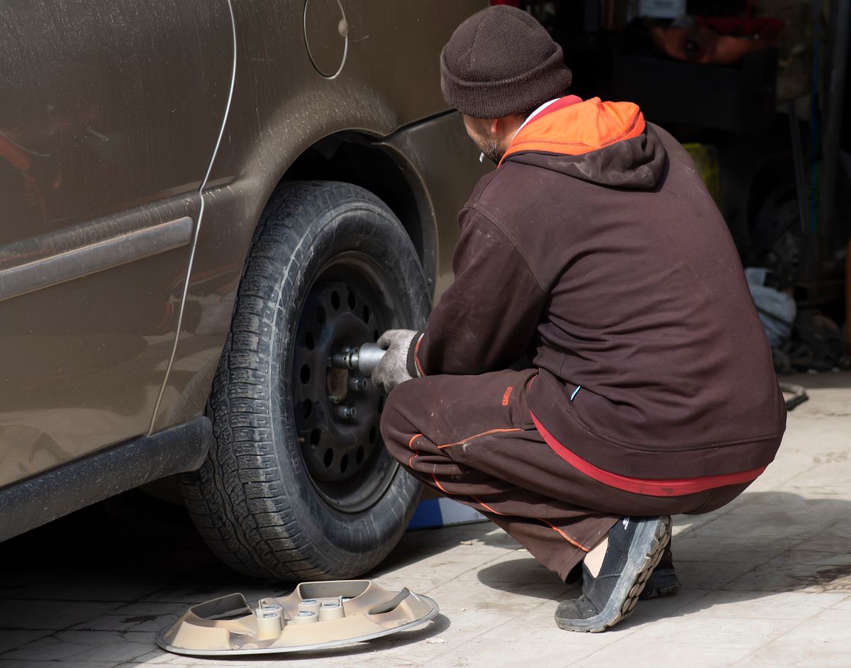 Mobile tire technician servicing a car tire at the roadside in Miami-Dade